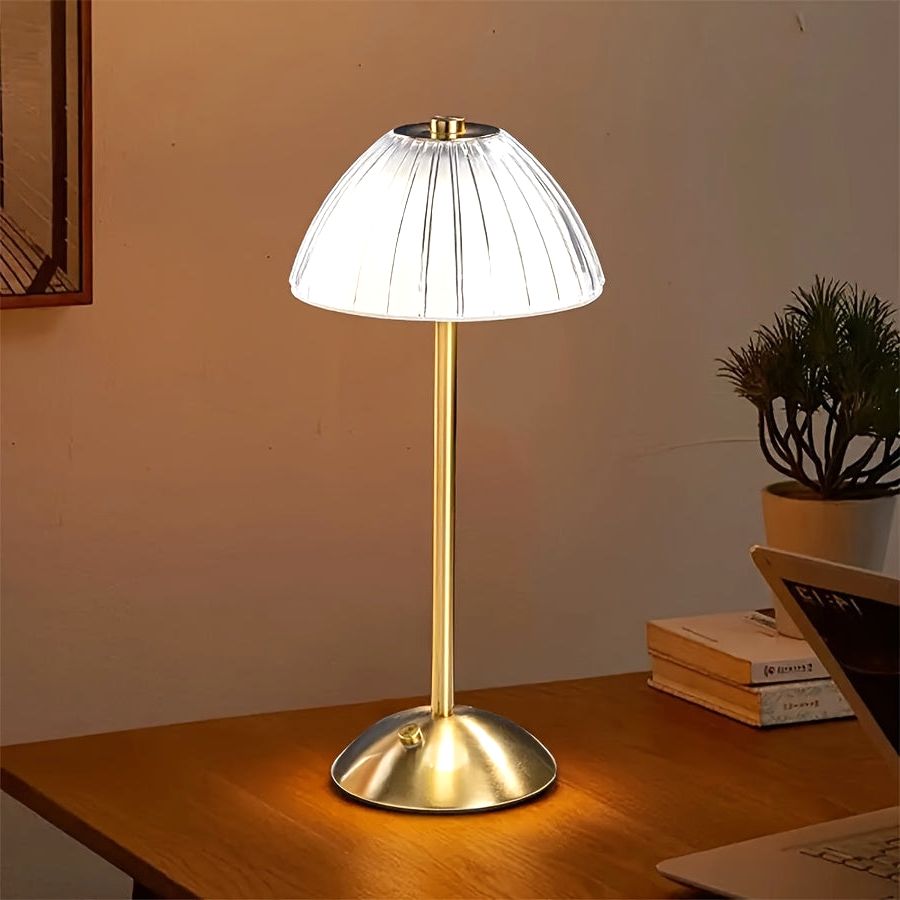 Luxe Glow USB rechargeable table lamp with an elegant gold finish and pleated shade, illuminated on a modern wooden desk, providing ambient light.